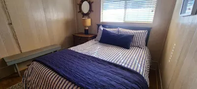 a bedroom with a bed with a blue blanket and a window at Lakeview Lodge, bookable boat slip! in Bass Lake