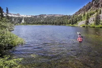 a person is standing on a paddle board in a river at Hidden Valley 114 I in Mammoth Lakes