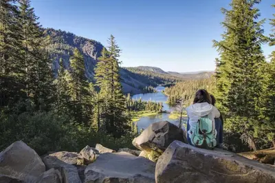 a woman sitting on a rock overlooking a lake at Hidden Valley 14 B in Mammoth Lakes
