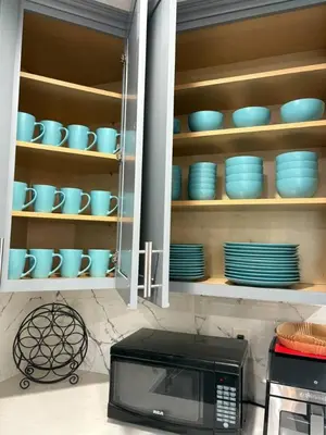 a kitchen with a microwave and blue dishes on shelves at Newly Renovated Lakefront with Dock in Bethel Island