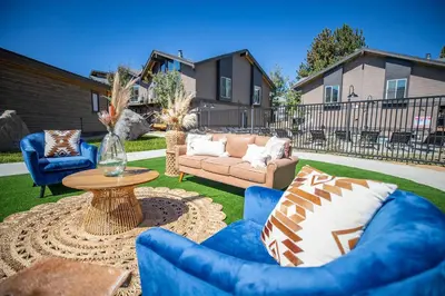 a patio with blue chairs and a table and a couch at Outbound Mammoth in Mammoth Lakes