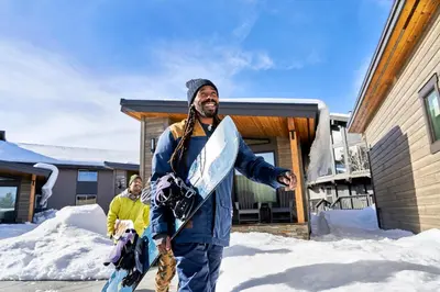 a man standing in the snow holding a snowboard at Outbound Mammoth in Mammoth Lakes