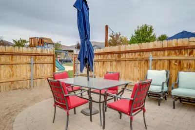 a patio table with red chairs and an umbrella at Hike, Play and Unwind Charming Reno Unit in Reno