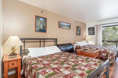 a bedroom with two beds and a table with a lamp at (A108) Studio Condominiums in Yosemite West