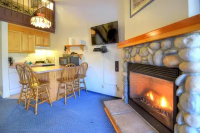 a living room with a fireplace and a table and chairs at (A211) Loft Condominiums in Yosemite West