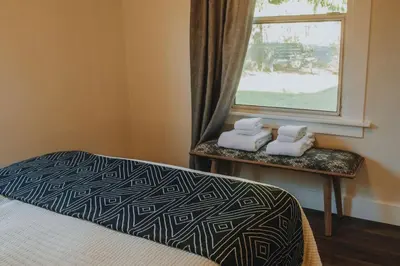 a bedroom with a bed and a window with towels at Yosemite Cottage Retreat- Half Block to Downtown in Mariposa