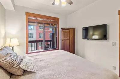a bedroom with a bed and a tv and a window at The Village #2408 - Village Center Cozy Getaway w Fireplace in Mammoth Lakes