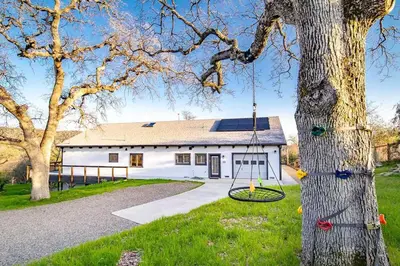 a tree with a swing in front of a building at Hilltop Luxury Yosemite Retreat with Spa, Pool, Views in Mariposa