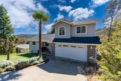a house with a palm tree and a garage at Yosemite Terrace View Retreat in Mariposa
