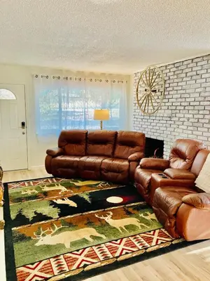 a living room with a brown leather couch and a rug at Ely Farm House - Near Yosemite National Park in Oakhurst