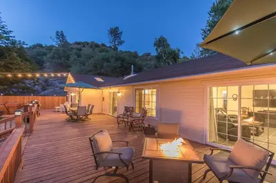 a deck with chairs and a table and a house at Sullivan House & SPA Near Yosemite, 8 Min to Town in Mariposa
