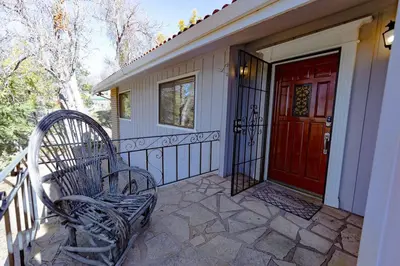 a porch with two chairs and a red door at Kindred Spirits Lodge near Yosemite & Bass Lake! in Oakhurst