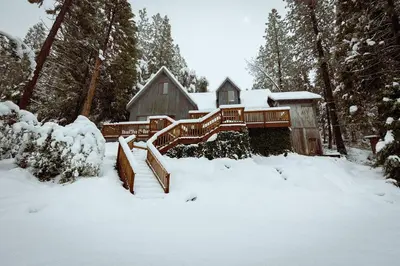 a house with a deck in the snow at Cozy Cabin Near Yosemite & Corlieu Falls in Oakhurst