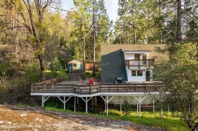 a home with a large deck in the woods at Acorn Falls, Bass Lake, Ca in Bass Lake