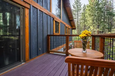 a wooden deck with a table and a vase of flowers at Boathouse in the Woods by Tahoe Getaways - Minutes to Lake Tahoe & Northstar in Kings Beach