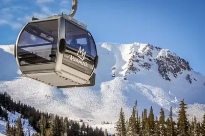 a ski lift with a snow covered mountain in the background at Mammoth Green - 207 in Mammoth Lakes