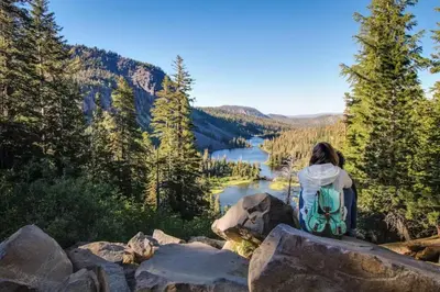 a woman sitting on a rock overlooking a lake at Summit 65 in Mammoth Lakes