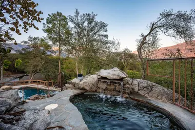 a large pool with a waterfall in a backyard at Prime Sequoia Stay Pool Hot Tub Sauna Views in Three Rivers
