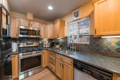 a kitchen with wooden cabinets and stainless steel appliances at The Ale Arths Retreat for 8 in South Lake Tahoe