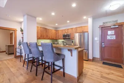 a kitchen with wooden cabinets and a bar with stools at Ironhorse Northstar Condo condo in Truckee