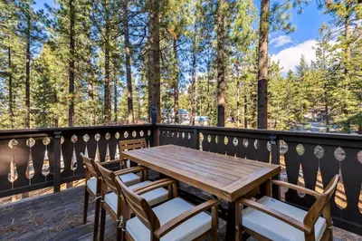 a wooden table and chairs on a balcony with trees at 1192 Timber Lane home in South Lake Tahoe