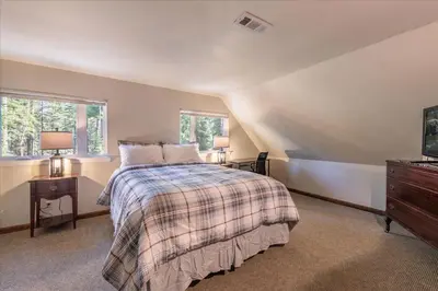 a bedroom with a bed and a desk and two windows at Fred's Retreat cabin in Homewood