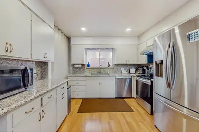 a kitchen with white cabinets and a stainless steel refrigerator at Mid-Century Tahoe Ranch House in South Lake Tahoe