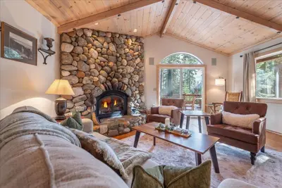 a living room with a large stone fireplace at Tahoe Pines Beach Retreat home in Homewood