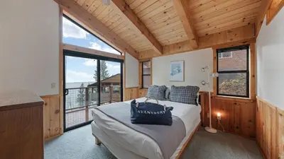 a bedroom with a bed and a large window at Cozy Donner Lake Cabin w Kayaks Forest Views Fireplace Quick Ski Resort Access Donner Lake Refuge by AvantStay in Truckee