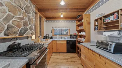 a kitchen with a stove and a stone wall at Cozy Donner Lake Cabin w Kayaks Forest Views Fireplace Quick Ski Resort Access Donner Lake Refuge by AvantStay in Truckee