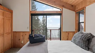 a bedroom with a bed and a large window at Cozy Donner Lake Cabin w Kayaks Forest Views Fireplace Quick Ski Resort Access Donner Lake Refuge by AvantStay in Truckee