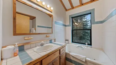 a bathroom with a sink and a tub and a mirror at Cozy Donner Lake Cabin w Kayaks Forest Views Fireplace Quick Ski Resort Access Donner Lake Refuge by AvantStay in Truckee
