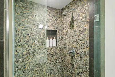 a bathroom with a shower with a stone wall at Luxury 3BR 3BA Condo Steps from Canyon Lodge Lift in Mammoth Lakes