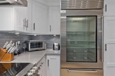 a kitchen with white cabinets and a stainless steel refrigerator at Luxury 3BR 3BA Condo Steps from Canyon Lodge Lift in Mammoth Lakes