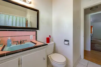 a bathroom with a sink and a toilet and a mirror at Hot Tub, Patio and Outdoor Games at Visalia Home in Visalia