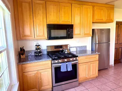 a kitchen with wooden cabinets and a stove top oven at Cozy Farm House with River access in Three Rivers