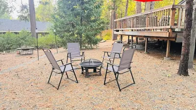 a group of chairs and a table with an umbrella at Cozy Cabin and Modern Stay in Arnold Near Bear Valley in Arnold
