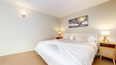 a bedroom with a large white bed with a picture on the wall at Western Slopes Villas #7 condo in Mammoth Lakes