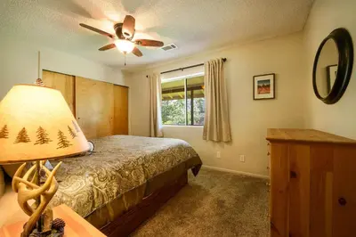a bedroom with a bed with a lamp and a window at Blue Bird Ranch in Oakhurst