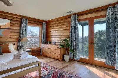 a bedroom with wooden walls and a bed and windows at Sierra Mountain View Retreat in Coarsegold