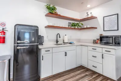 a kitchen with white cabinets and a stainless steel refrigerator at The Four Daughters Inn in Oakhurst