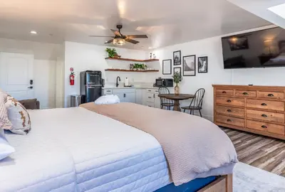 a bedroom with a large bed and a kitchen at The Four Daughters Inn in Oakhurst