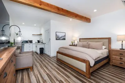 a bedroom with a large bed and a kitchen at The Four Daughters Inn in Oakhurst