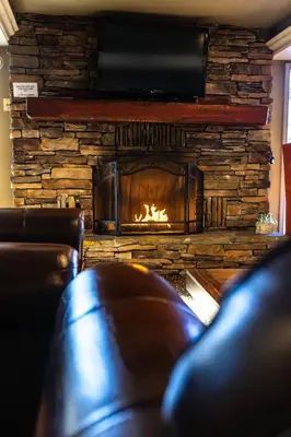 a living room with a fireplace and a leather couch at The Sierra House in Mammoth Lakes