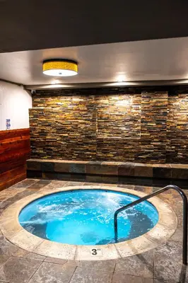 a hot tub in a room with a stone wall at The Sierra House in Mammoth Lakes