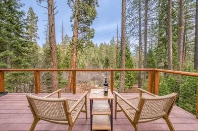 a deck with two chairs and a table with a bottle of wine at Tahoe City Retreat - Creekside Deck & Hot Tub in Tahoe City