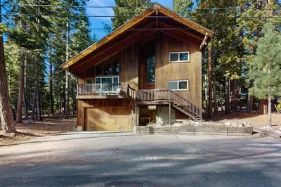 a house in the woods with a porch and a balcony at Tahoe Alpine and Lake Escape in Carnelian Bay