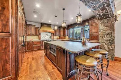 a kitchen with wooden cabinets and a stone wall at South Lake Tahoe Escape - Private Hot Tub Pool in South Lake Tahoe