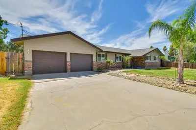 a house with a garage and a palm tree at 2 Mi to UC Merced Modern Home with Private Yard in Merced