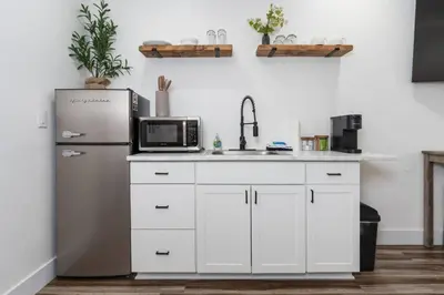 a kitchen with white cabinets and a refrigerator at Ryann Suite at The Four Daughters Inn in Oakhurst